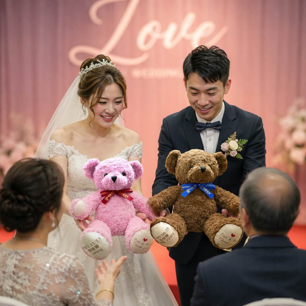 Bride and groom presenting Toheartworld custom exact birth weight bears to their parents at a wedding